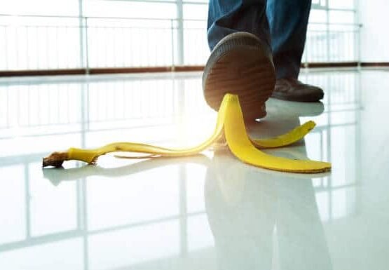 Businessman stepping on banana peel on the sidewalk.