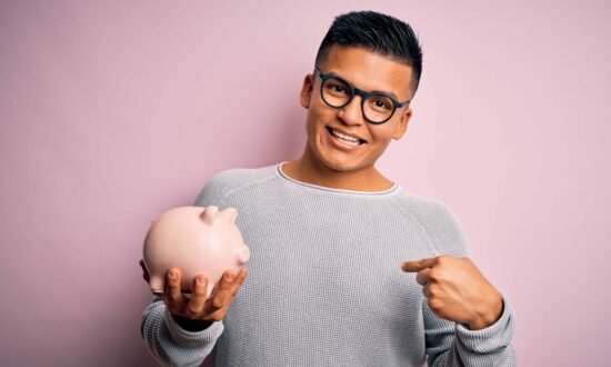 Importance pension employeur Young handsome latin man holding piggy bank over isolated pink background with surprise face pointing finger to himself